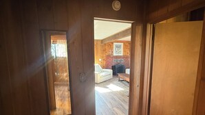 Un couloir intérieur aux murs en bois, avec une porte donnant sur un espace de vie.