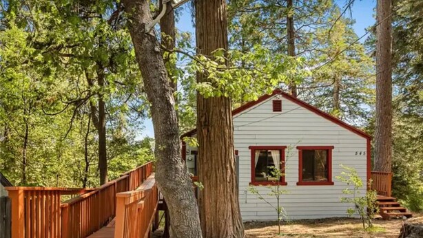 Une cabane avec un toit rouge et des murs blancs, entourée d’arbres.