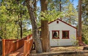 A cabin with a red roof and white walls, surrounded by trees.