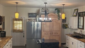 Una cuina moderna amb una illa central, electrodomèstics d'acer inoxidable i il·luminació penjant.