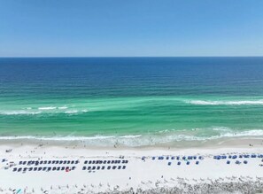 A beach with a clear view of the ocean, a sandy shore, and several umbrellas.