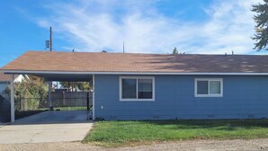 A single-story house with a covered porch, a fenced yard, and a clear blue sky. - Lovely family and  pet friendly townhome in charming Fruitland Idaho (Fruitland)