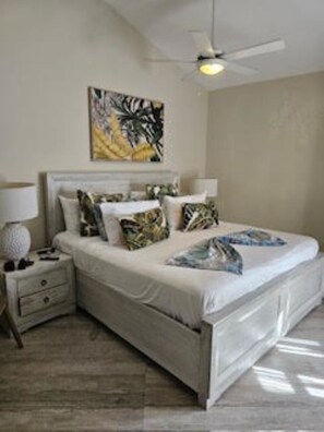 A bedroom with a bed, nightstands, a ceiling fan, and a wall painting. - Magnificent 3 bedroom GOLD bracelets
all-inclusive experience Luxurious villa (Puerto Plata)