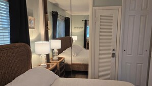 Une chambre d’hôtel comprenant un lit, une table de chevet avec des lampes, un miroir et une armoire.