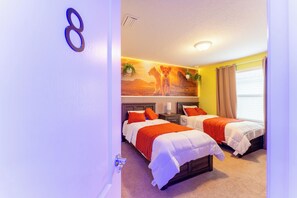 Une chambre d’hôtel avec deux lits, une fresque murale, une plante et une fenêtre avec des rideaux.