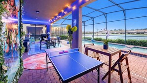 Ein Außenpoolbereich mit Pingpongtisch, Sitzgelegenheiten und Blick aufs Wasser.