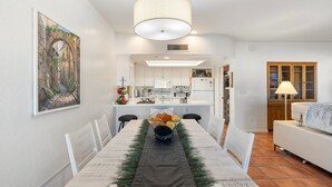 A dining area with a long table, chairs, a chandelier, and a kitchen in the background. - Spacious and quiet 2-bedroom casita with view in Fountain Hills (Fountain Hills)