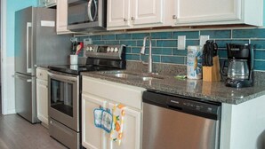 A kitchen with white cabinets, stainless steel appliances, a microwave, a coffee maker, and a dishwasher. - Myrtle Beach Quiet Coastal Getaway | Great Ocean & Coast Views (Myrtle Beach)