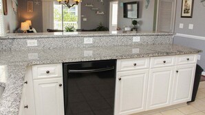 A kitchen with granite countertops, white cabinetry, a black dishwasher, and a ceiling fan. - Heatherston 1063 Walk to Tee Time Daily overlooking the pool area! (Myrtle Beach)