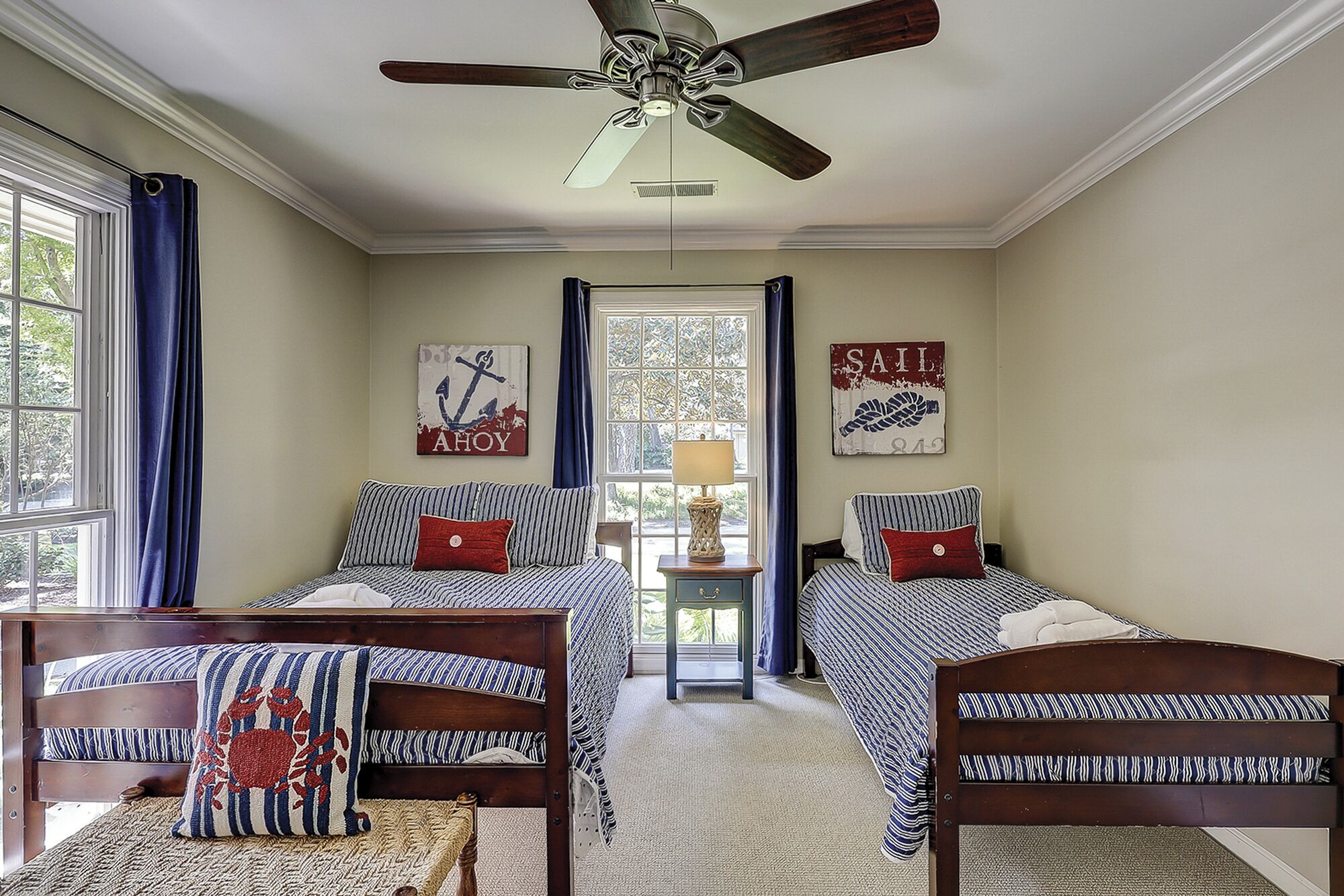 Ein Schlafzimmer mit zwei Betten, einem Deckenventilator und maritimer Dekoration.