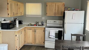 A kitchen with wooden cabinets, a white refrigerator, a stove, and a dining table with chairs.
