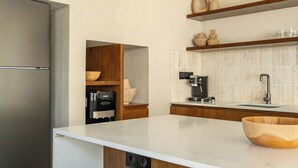 Une cuisine moderne dotée d’un réfrigérateur en acier inoxydable, de meubles en bois, d’un plan de travail en marbre et d’une machine à café.
