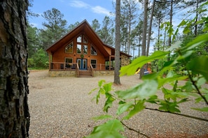 A cabin with a stone foundation, large windows, and a porch.