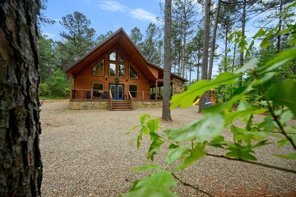 Une cabane avec des fondations en pierre, de grandes fenêtres et une véranda.