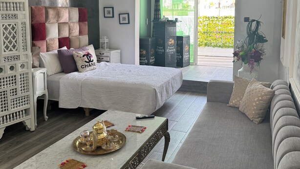 A modern bedroom with a bed, a seating area, and a view of a garden. - Studio downtown Rabat terrace (Rabat)