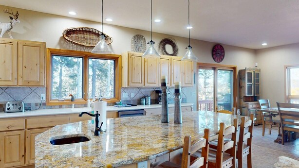 A spacious kitchen with wooden cabinets, a granite countertop, and pendant lighting. - Views | Hot Tub | Pet Friendly | Sunrise Ridge (Angel Fire)
