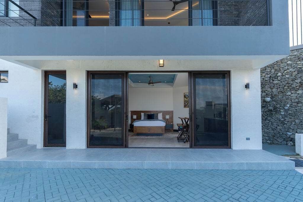 Ein modernes, zweistöckiges Haus mit einer großen Glasdoor, die zu einem Schlafzimmer mit Bett und Schreibtisch führt.
