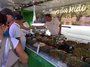 Uma banca de mercado com azeites e azeitonas variadas.