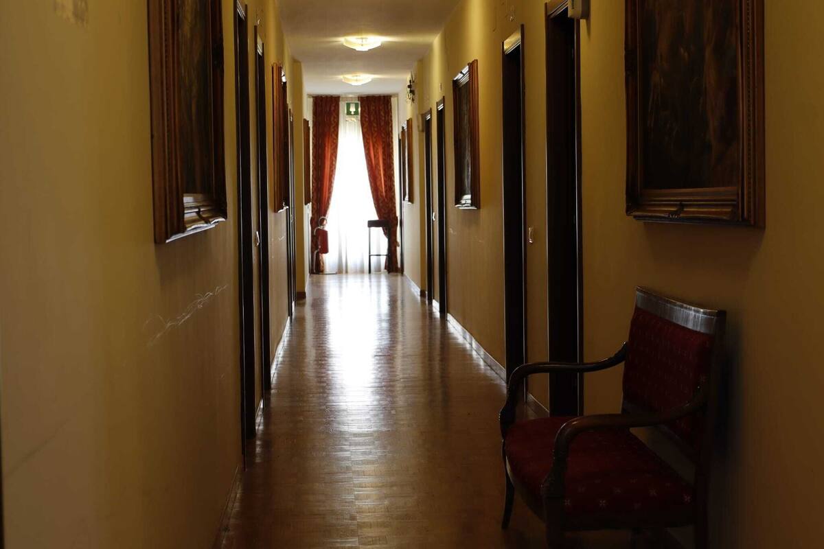 A hotel hallway with wooden floors, a bench, and doors leading to rooms.