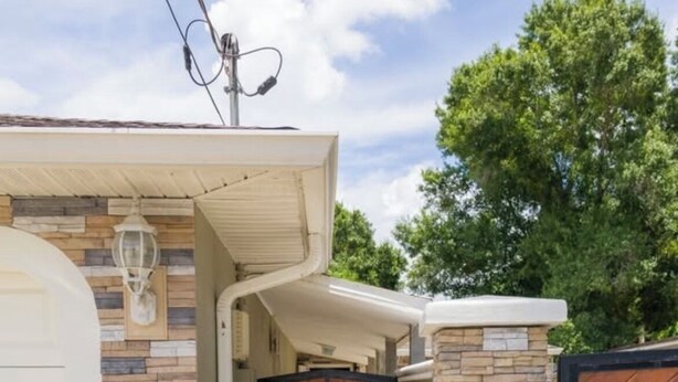 A modern house with a stone facade, a wooden garage door, and a gated entrance. - Unit B Cozy 1 bedroom 1 bath Studio. (Tampa)