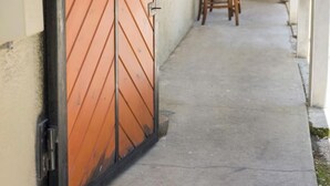 A corridor with a large wooden gate, a chair, and a door at the end. - Unit B Cozy 1 bedroom 1 bath Studio. (Tampa)