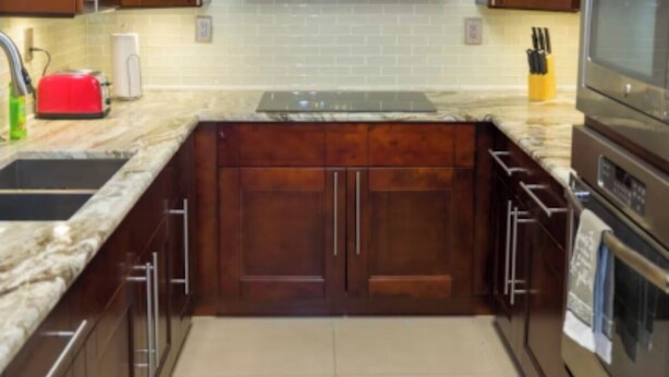 Una cocina con armarios de madera oscura, una campana extractora de acero inoxidable, encimera de granito y horno empotrado.