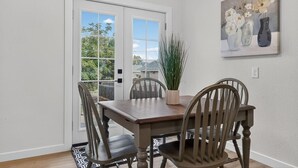 A dining area with a wooden table and chairs, a potted plant, and a painting on the wall. - Modern 3 bedroom Home in Prime Location! 7 guests (Lewiston)