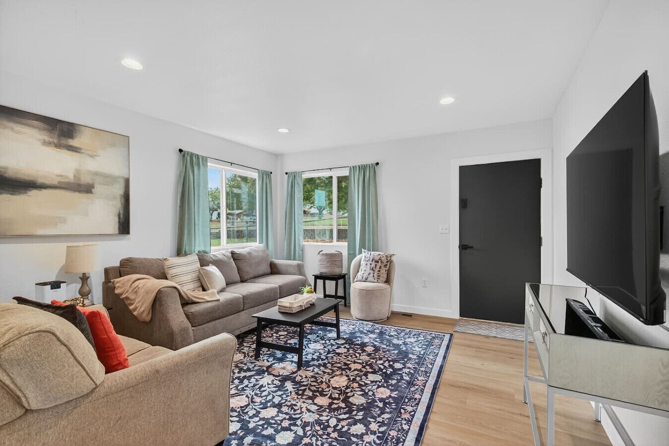 A modern living room with a sofa, armchair, coffee table, and a TV.