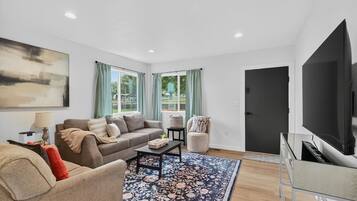 A modern living room with a sofa, armchair, coffee table, and a TV.