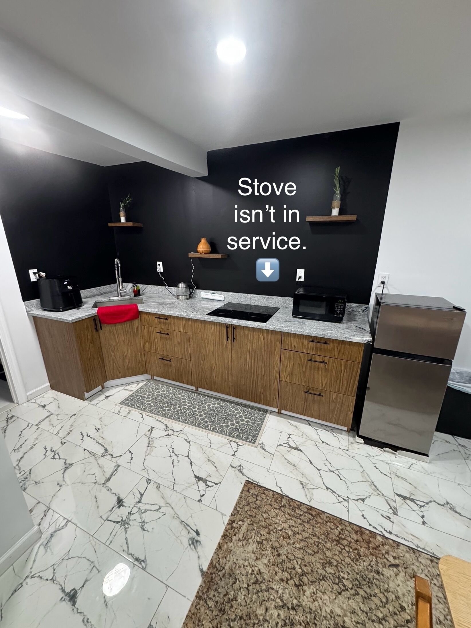 Een koelkast, een magnetron, een waterkoker, kookgerei, borden en bestek