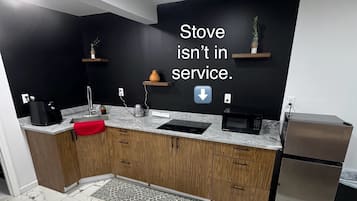 Een koelkast, een magnetron, een waterkoker, kookgerei, borden en bestek