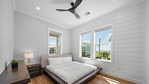 Ein Schlafzimmer mit Bett, Schreibtisch, Lampe und Deckenventilator.