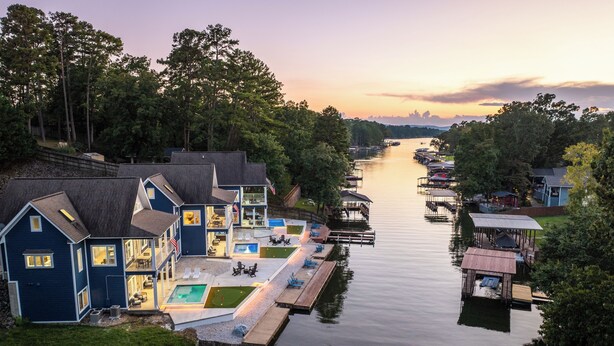 Een pand aan het water met meerdere huizen, een steiger en een rustige rivier.