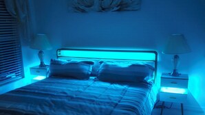 Un dormitorio con una cama, dos mesitas de noche y una lámpara de pared.