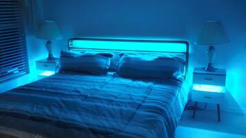 Une chambre à coucher avec un lit, deux tables de chevet et une lampe fixée au mur.