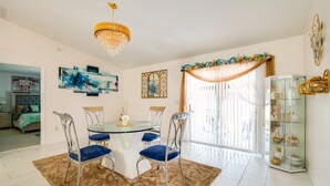 Comedor con mesa de vidrio, cuatro sillas, candelabro y una vitrina decorativa de vidrio.