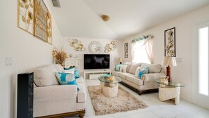 Una sala de estar con sofá, dos sillones, una mesa de centro, televisor, decoración en la pared y chimenea.
