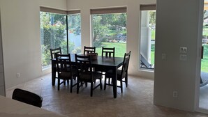 Un área de comedor con una mesa y sillas, ventanas amplias y un ventilador de techo.