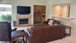 Una sala de estar con chimenea, televisor, sofá y ventilador de techo.