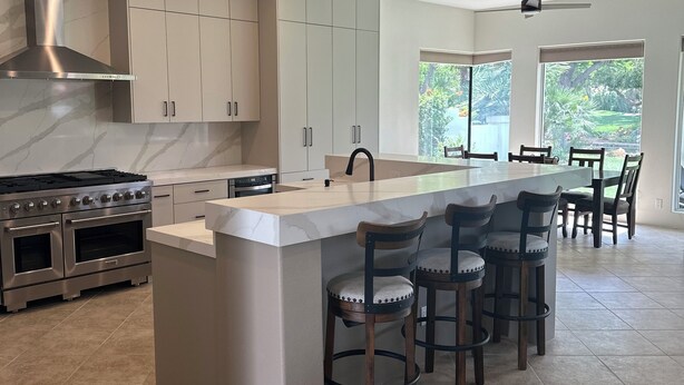Una cocina moderna con una isla grande, electrodomésticos de acero inoxidable y vistas al exterior.