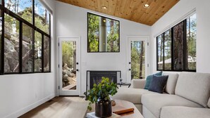 A modern living room with a fireplace, large windows, and a cozy seating area.