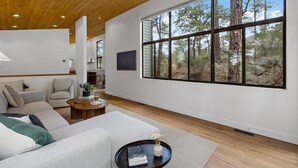 A spacious living room with a large window, a sofa, a coffee table, and a view of the outdoors.