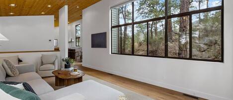 A spacious living room with a large window, a sofa, a coffee table, and a view of the outdoors.