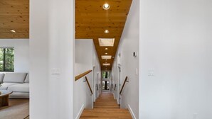 A modern interior with a wooden staircase, white walls, and a visible living area with a sofa and coffee table.
