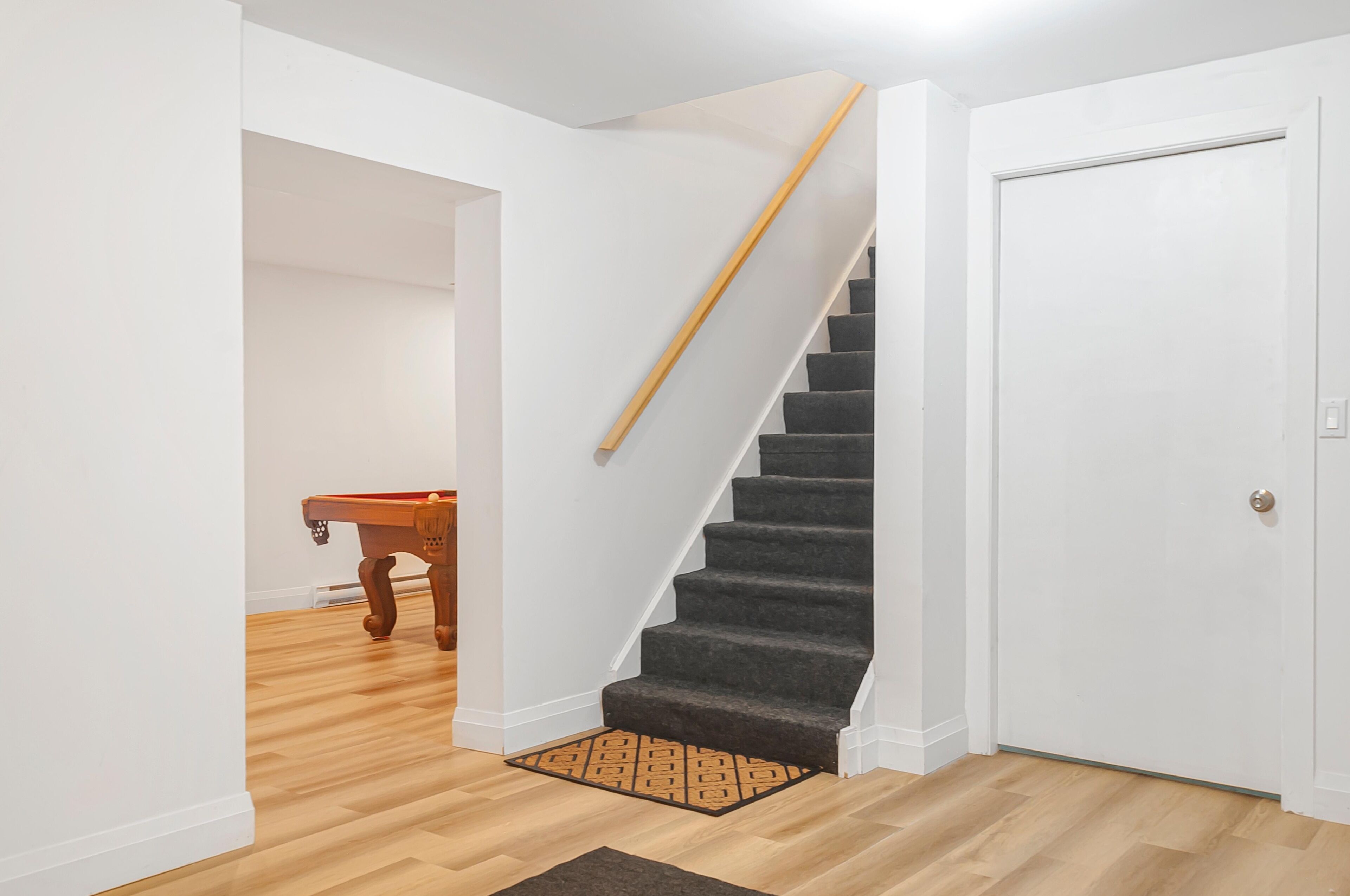 A staircase with carpeted steps leading to a white door. A wooden table is visible in the background.