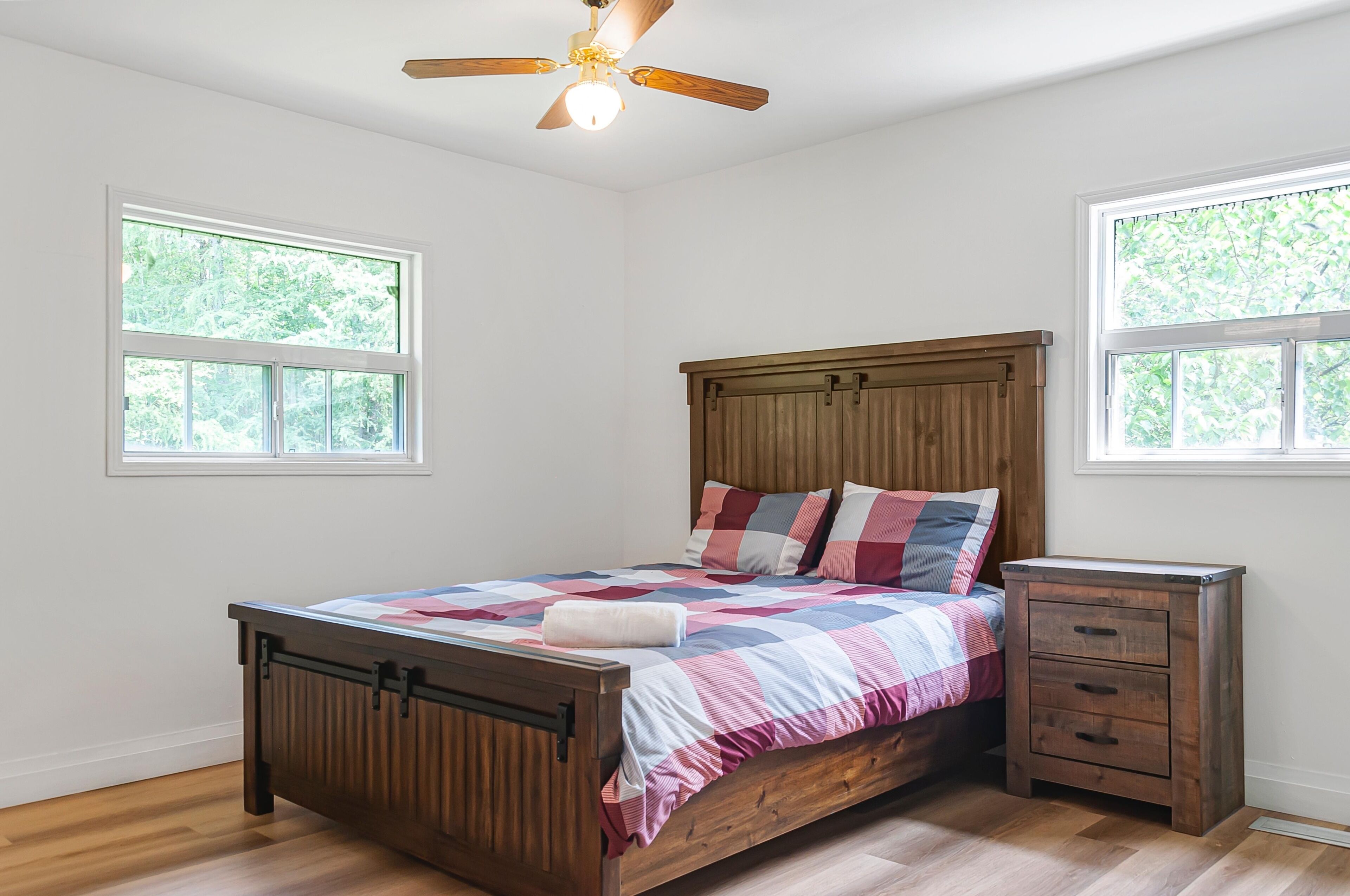A bedroom with a wooden bed, a nightstand, and a ceiling fan.