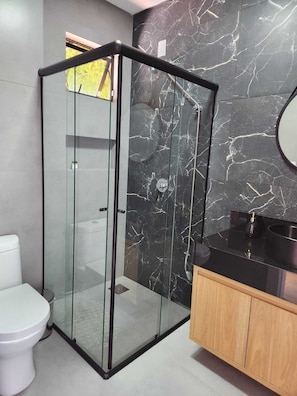 A modern bathroom with a glass-enclosed shower, a toilet, and a vanity with a sink. - Wonderful house with spectacular views of the Uruguay River - Goio En - Chapecó-SC (Chapecó)