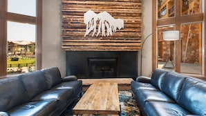 Una sala de estar moderna con sofás de cuero, una mesa de centro de madera y una chimenea con un revestimiento de madera.