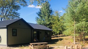 A single-story building with a sloped roof, a front porch, and a picnic table in front.