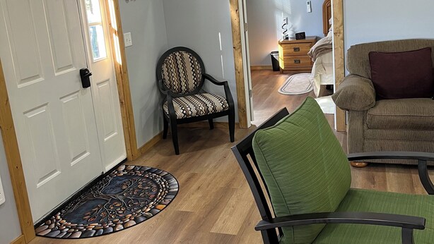 A living room with a green sofa, a patterned armchair, a wooden coffee table, and a small rug.